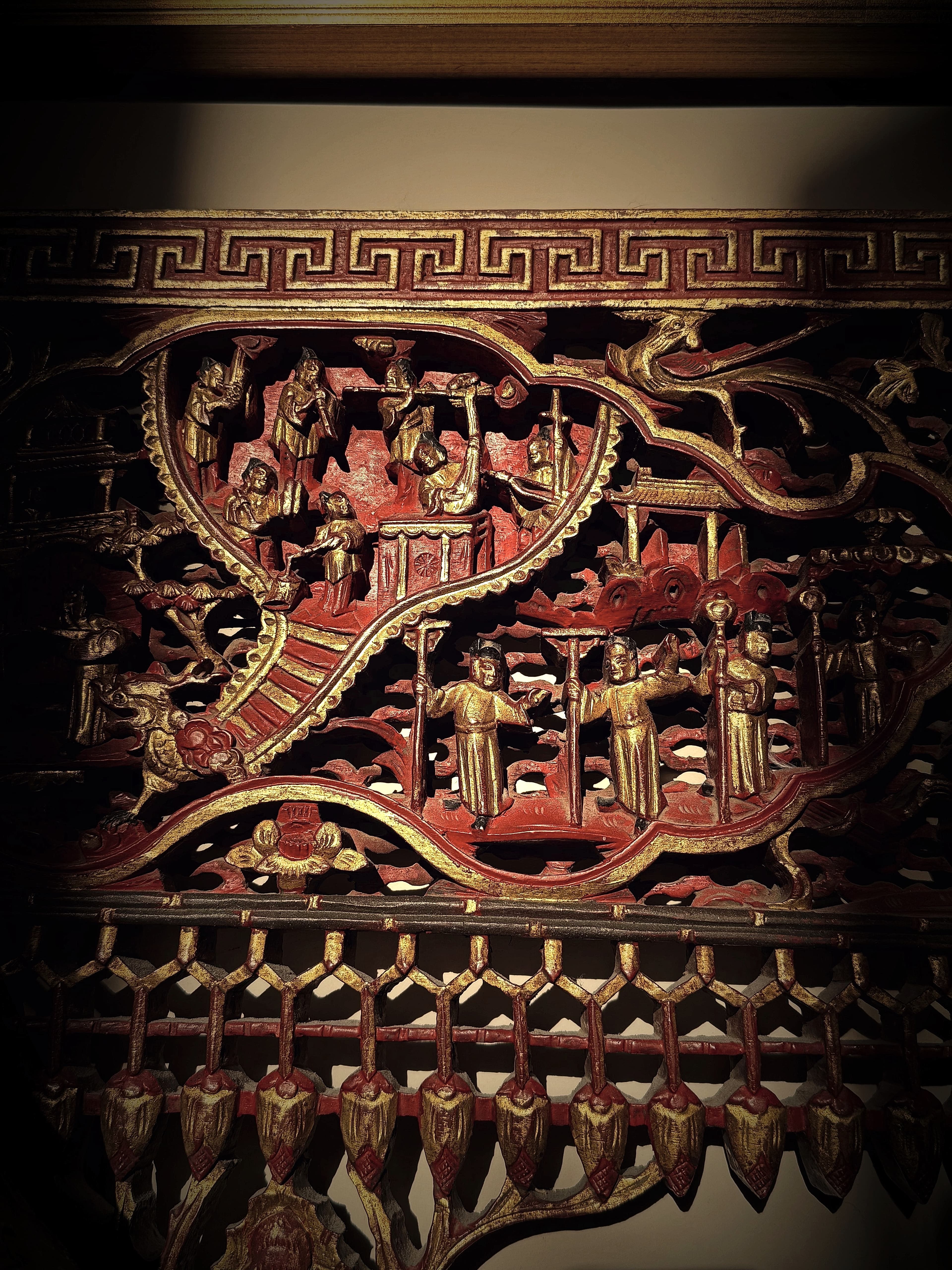 A carved frieze in red lacquer and gilt, figures in procession